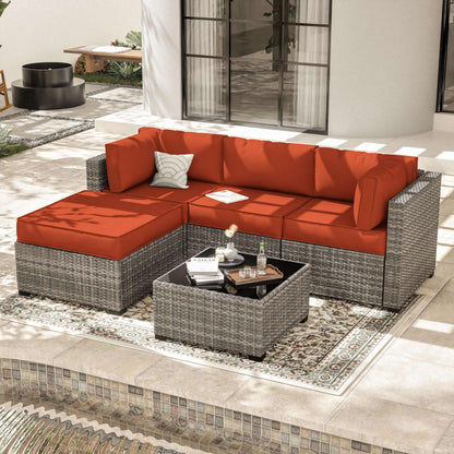 Modern outdoor patio with gray wicker sectional sofa with red cushions and matching coffee table
