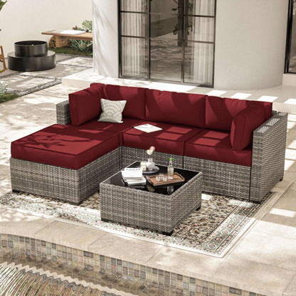 Outdoor patio with gray wicker sectional sofa featuring red cushions and patterned rug by a pool
