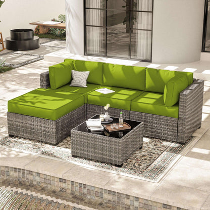 Outdoor patio with grey wicker sectional sofa featuring bright green cushions and a matching coffee table on a patterned rug