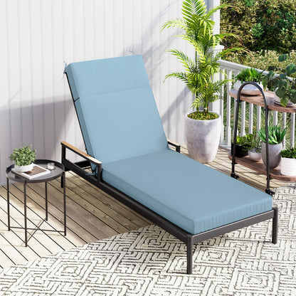 lounge chair with blue lounge cushion on a patio with plants and a small table.
